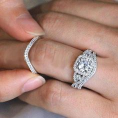 a woman's hand holding an engagement ring with diamonds on the band and side stones