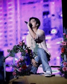 a male in a white shirt is on stage and holding a microphone to his ear