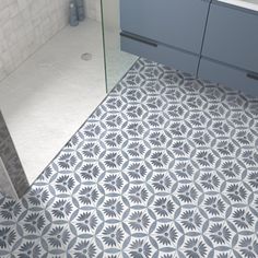 a bathroom with blue and white tiles on the floor, sink and shower stall area