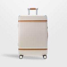 a white suitcase with brown trim on the handle and wheels, against a gray background