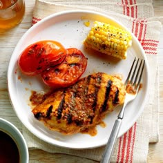 a white plate topped with grilled chicken, tomatoes and corn on the cob