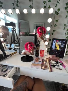 a woman with pink hair sitting in front of a mirror looking at her makeup and make - up