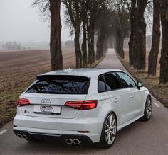 a white car parked on the side of a road next to some trees and grass