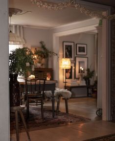 a dining room table and chairs with candles on the wall behind them in front of an open doorway