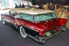 an antique car is on display in a showroom with people looking at the cars