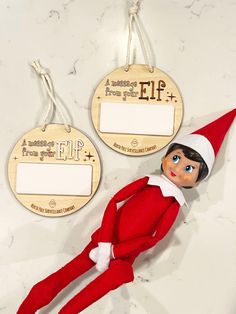 an elf is laying on the counter next to two tags