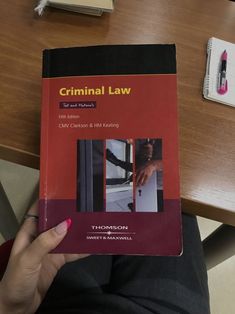 a person holding up a book about the law in front of a desk with books on it