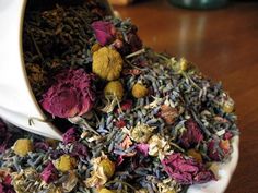 a white cup filled with lots of different types of flowers and herbs on top of a wooden table