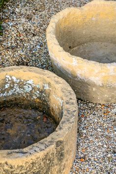 two cement bowls sitting on top of gravel