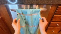 a person holding up a towel in front of an oven