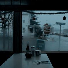 a table with two sodas and some food on it in front of a window