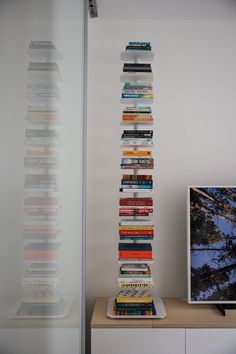 a tall stack of books sitting on top of a table next to a flat screen tv