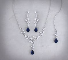 a necklace and earring set with blue stones on a silver chain, featuring leaves