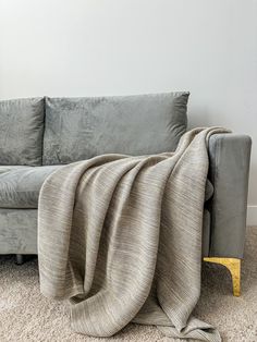 a couch with a blanket on top of it next to a chair and wall in the background