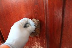 a person in white gloves cleaning a wooden door