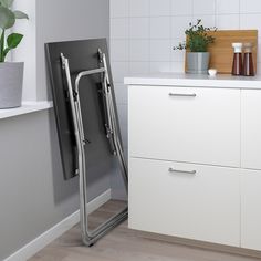 a kitchen with white cupboards and a black refrigerator freezer next to a plant