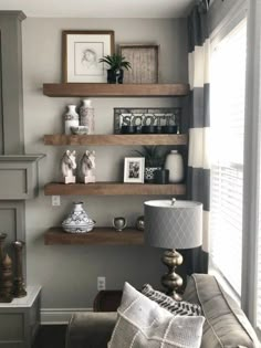 a living room with some shelves on the wall and a lamp in front of it