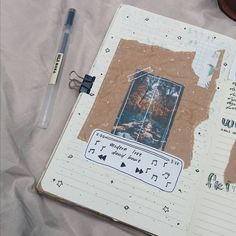 an open notebook with music notes on it and a pen sitting next to the pages