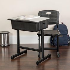 a black desk and chair in front of a wall with a backpack on the floor