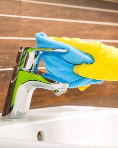 a person in yellow gloves is cleaning a sink with a blue and yellow rag on it