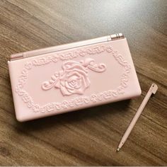 a pink purse sitting on top of a wooden table next to a pen and pencil