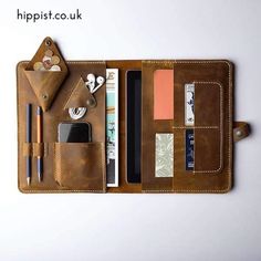 a leather wallet with various items in it, including pens and pencils on the side