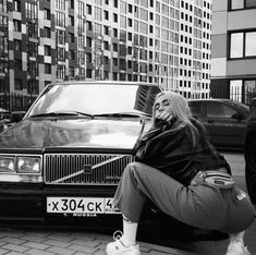 a woman sitting on the ground next to a car