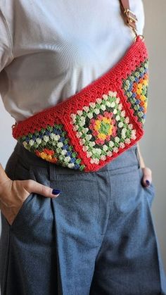 a woman wearing a red crocheted belt with colorful flowers on the front and sides