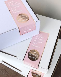 two boxes that have some kind of pink and gold label on them, sitting on top of each other