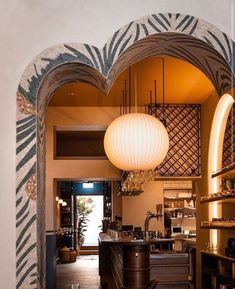 an arch in the middle of a kitchen with a light hanging from it's ceiling