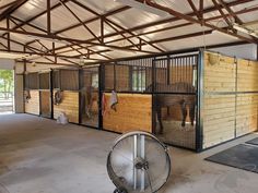 the inside of a building with several stalls and horses in them, some on wheels