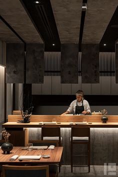 a man sitting at a table in front of a counter with sushi on it