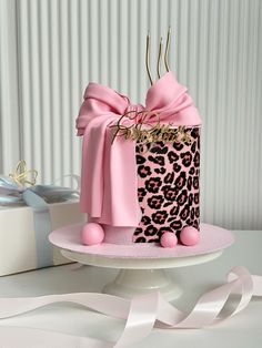 a pink and black leopard print cake on a white plate with ribbon around the edge