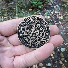 a hand holding a black and gold medallion with an image of a bird on it