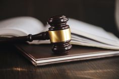 a wooden judge's gavel sitting on top of a binder next to an open book