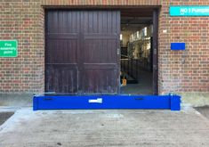 a blue barricade in front of a brick building with no parking signs on it