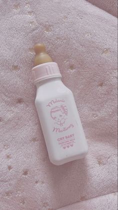 a baby bottle sitting on top of a pink blanket