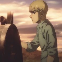 a young man standing next to a metal object in front of a cloudy sky with clouds