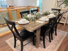 a dining room table is set with plates and place settings for four, along with black chairs