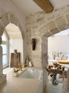 a kitchen with stone walls and an arched doorway leading to the living room, dining area