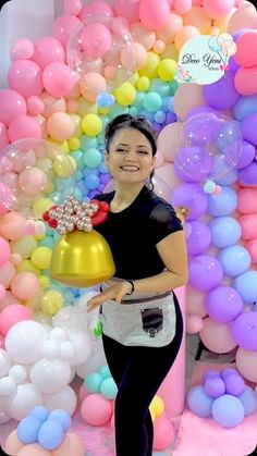 a woman standing in front of balloons with a cake on her plate and a bell