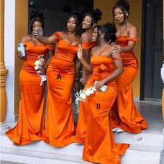 a group of women in orange dresses standing on steps