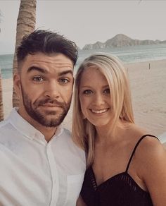 a man and woman standing next to each other on the beach with palm trees in the background