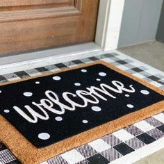 a welcome mat on the front door with white and black checkered rugs next to it