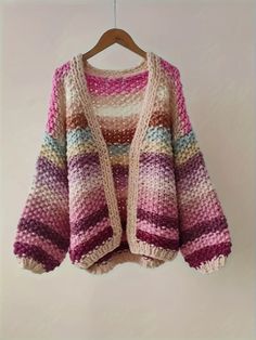 This sweater is a cozy, oversized knit cardigan with a gradient color pattern. It features a variety of pastel and muted hues, blending seamlessly from one color to the next. The color palette includes shades of pink, purple, beige, and hints of blue and green, creating a soft and dreamy appearance. The knit fabric is chunky and textured, providing warmth and a comfortable fit. The sweater has a loose, relaxed silhouette with dropped shoulders and wide sleeves, giving it an effortlessly chic and Multicolor Open Knit Cardigan, Pastel Long Sleeve Sweater For Winter, Multicolor Open Knit Winter Sweater, Multicolor Open Knit Sweater For Winter, Winter Multicolor Open Knit Sweater, Trendy Pink Soft Knit Sweater Coat, Casual Pink Soft Knit Sweater Coat, Multicolor Oversized Open Knit Sweater, Oversized Multicolor Open Knit Sweater