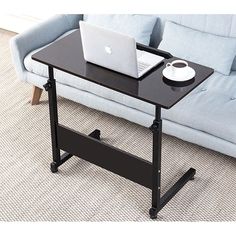 a laptop computer sitting on top of a black table next to a blue couch in a living room