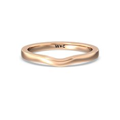 a gold wedding band with the word w c in black lettering on it, and a curved