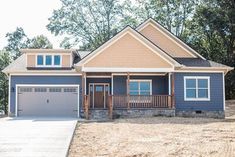 a blue house with two garages in the front yard and trees on the other side