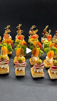 miniature sandwiches are arranged on small plates with fruit and veggies in the middle