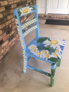 a painted chair sitting in front of a brick wall with daisies on the seat